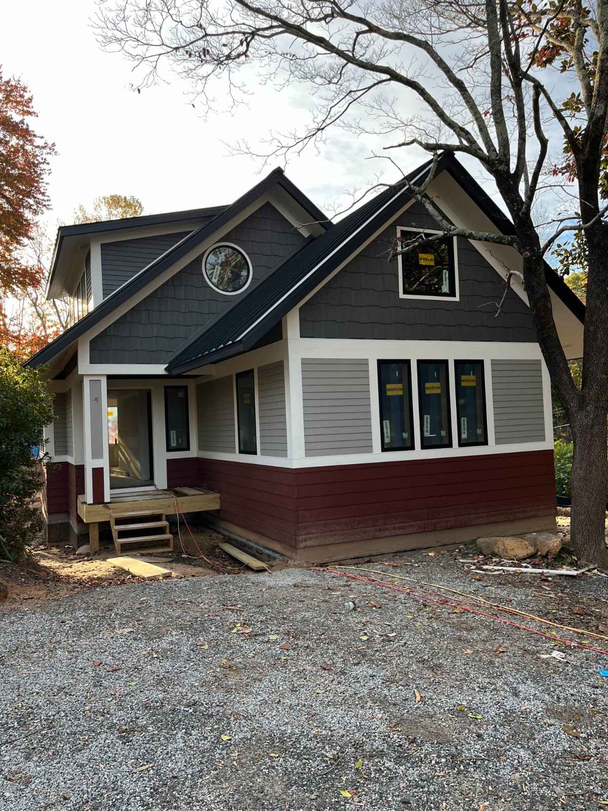 Modern residential exterior showcasing a multi-colored siding installation with charcoal shingles and light gray lap siding