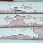 Severely peeling and flaking exterior paint on wood siding showing signs of coating failure.