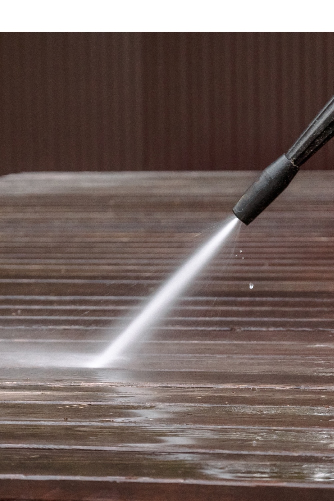High-pressure water spray cleaning a wooden deck surface during a professional pressure washing service by A2 Painting in Hendersonville NC