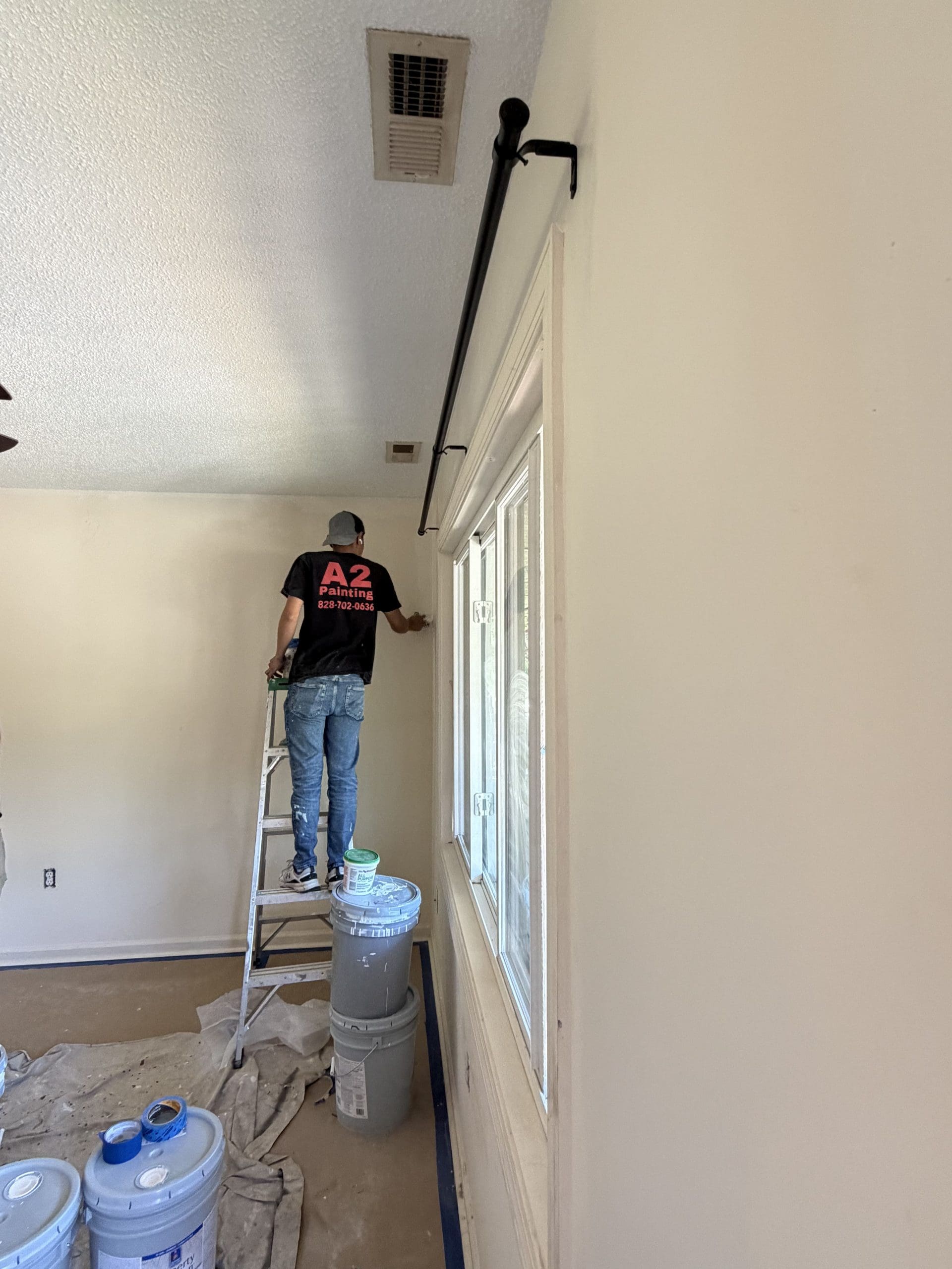 A2 Painting crew member prepping a wall near the ceiling as interior painters in Etowah, NC