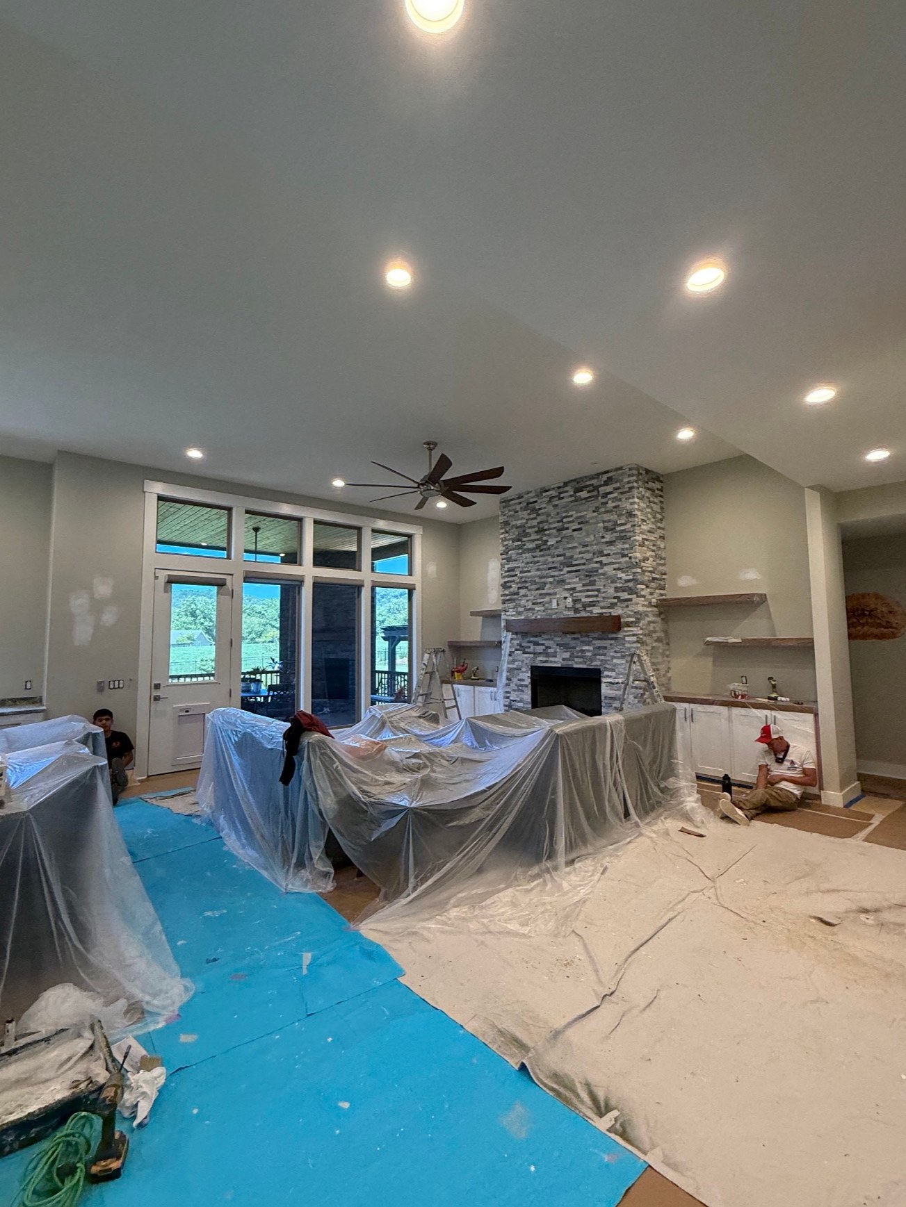 Large living room with stone fireplace prepped for interior painting