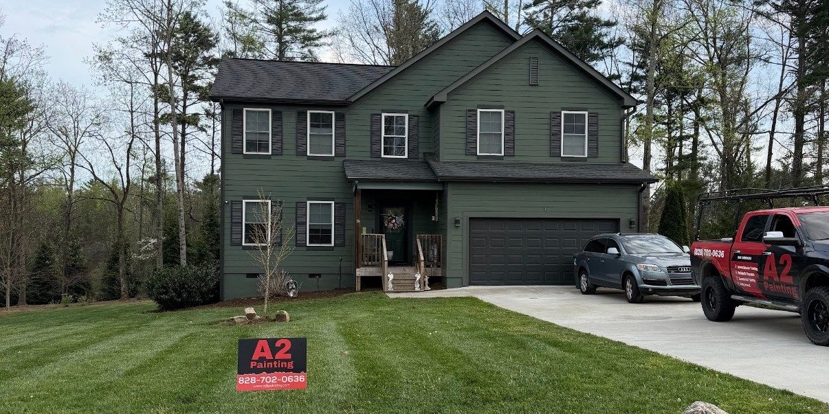 Two-story green home exterior painting with A2 Painting yard sign